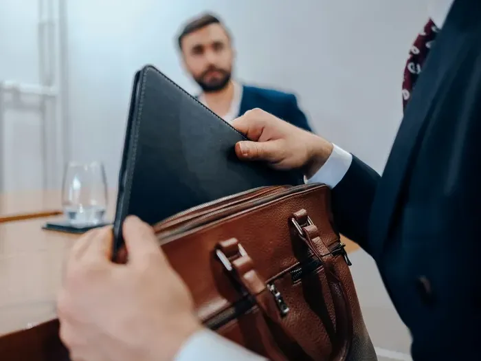 Businessman holding a leather briefcase and folder during a professional meeting, showing local business services
